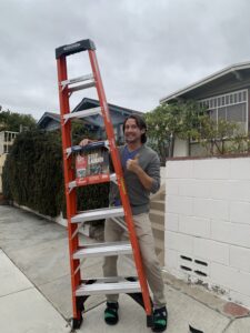 A man excitedly holds an orange 8-foot ladder. 