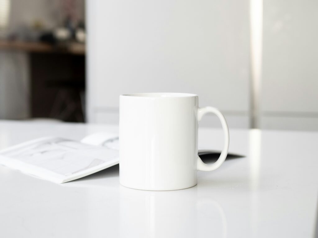 A white coffee mug sits on a white table. 